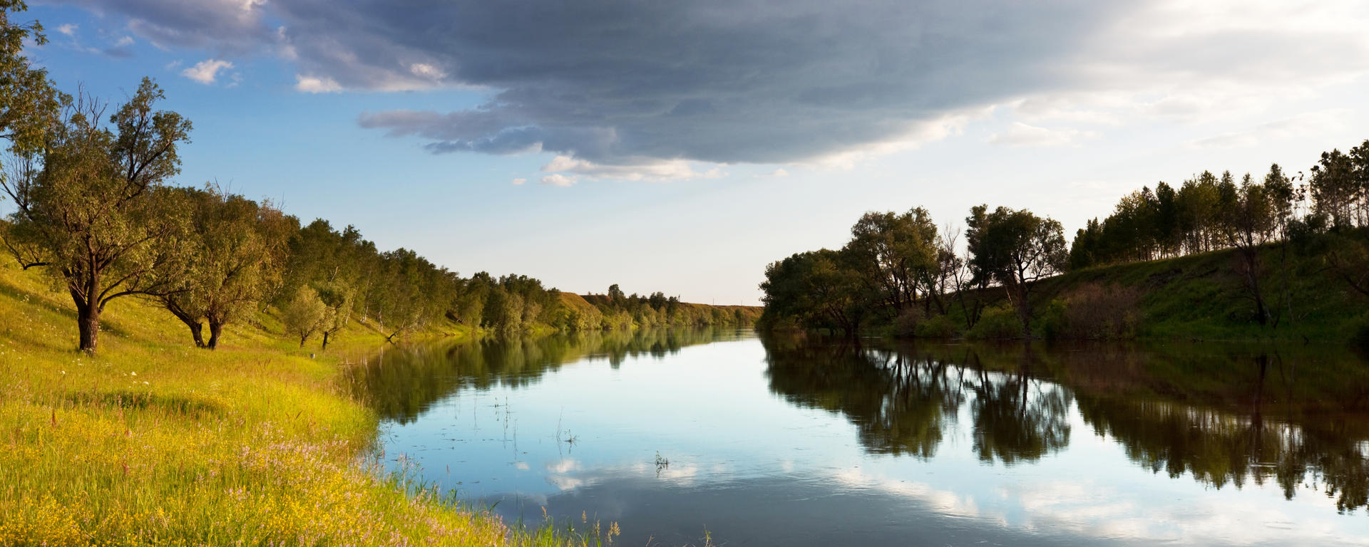 A river rounds the bend of a river valley under a moody sky