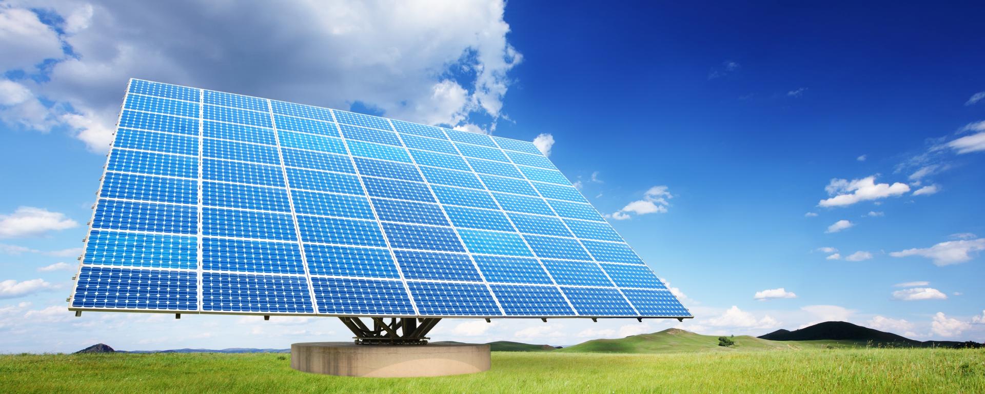 A large solar panel sits in a field of bright green grass